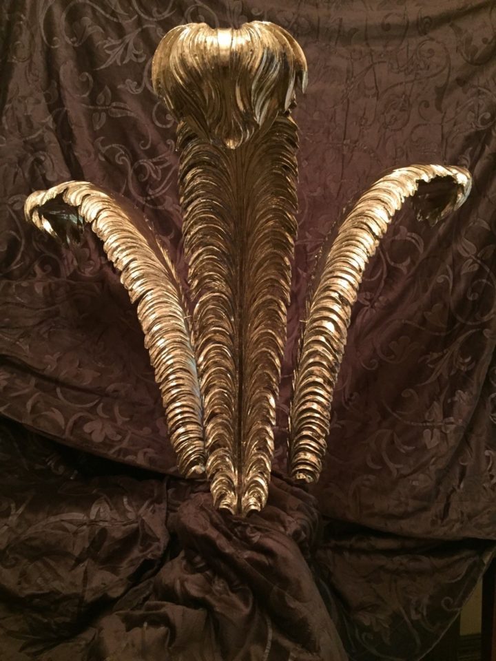 Three large, woodern plumes that have been gilded.